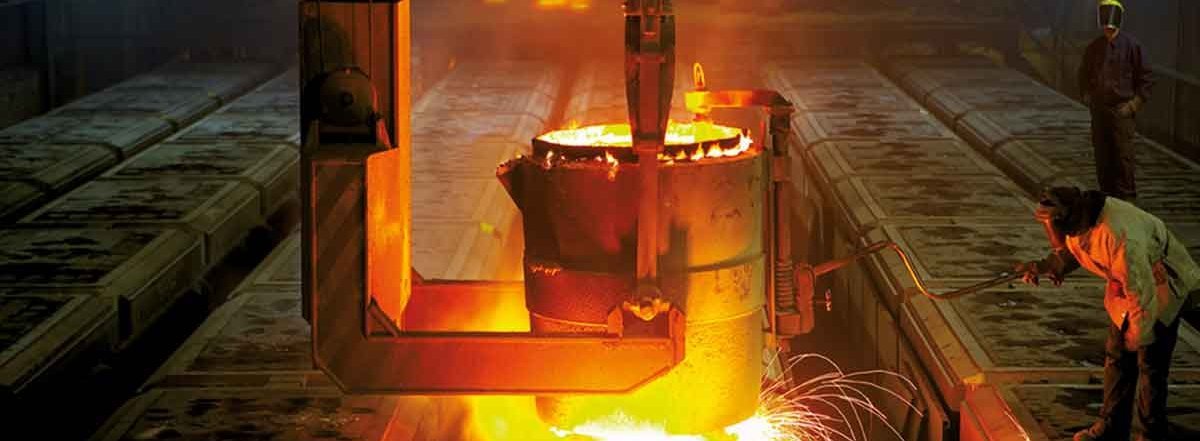 Foundry environment with intense glow of molten metal being poured, workers in protective gear ensuring precision.