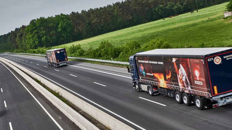 Two trucks on a highway with greenery in the background; the closer truck has a Foseco Foundry banner on the side.