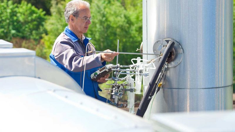 A man measuring the atmosphere with a specific device. He wears a blue collar.