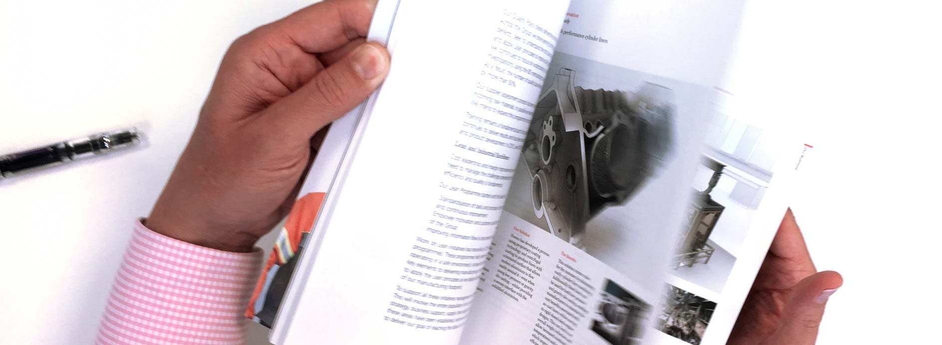 An individual flipping through a technical book on metallurgy, highlighting a detailed image of a metallic component, symbolizing continuous learning and industry expertise.