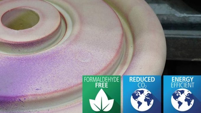 A hand applying a color-changing coating on a round foundry mold with eco-friendly icons for formaldehyde-free, reduced CO2, and energy efficiency