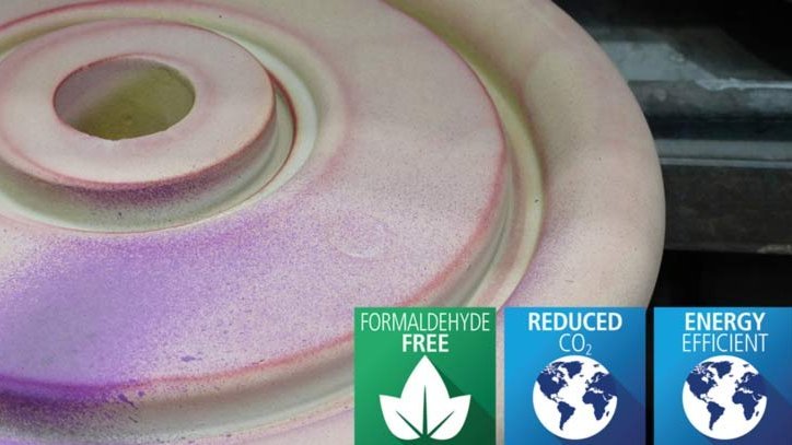 A hand applying a color-changing coating on a round foundry mold with eco-friendly icons for formaldehyde-free, reduced CO2, and energy efficiency