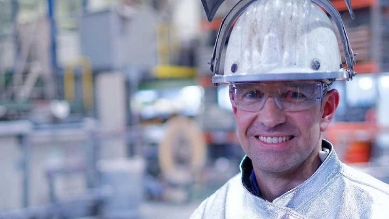 Foundryman with Safety Glassed and Helmet in a Foundry. It has a blurry background