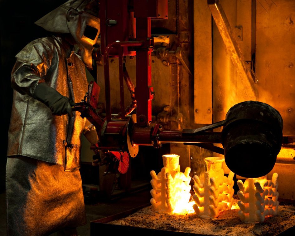 Lost wax process of Investment casting in iron foundry. Foundryman pouring molten iron