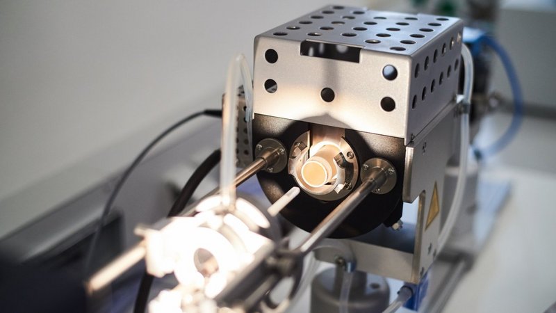 Close-up of a modern heating microscope in a lab environment, focusing on the precision element where samples are analyzed under controlled temperature conditions