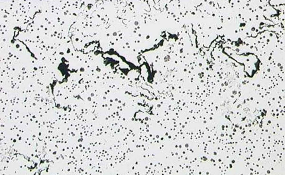 Micrograph of a metallic alloy showing the distribution of different phases within the matrix, with a scale indicating the image covers a 1 millimeter section.