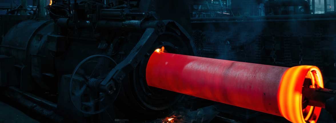 Centrifugal casting pipe. The casting is glowing because of the molten metal, in the background it is dark and a bit of fume.