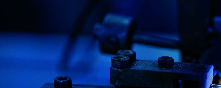 Close-up of industrial machinery components under blue lighting.