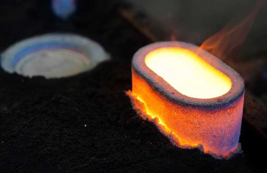 Close-up of FEEDEX NF1 feeder sleeves in use, showcasing the exothermic reaction with visible flames, designed for non-ferrous foundries.