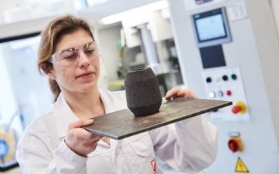 A female laboratory technician examining a foundry feeder sleeve, highlighting quality control in a modern lab setting.